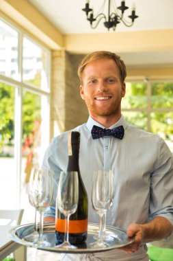Restoranda şarap servisi yapan kendinden emin genç garsonun portresi.
