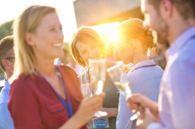 Ofis partisinde elde edilen başarıyı kutlamak için elinde şampanya kadehiyle gülümseyen genç girişimci.