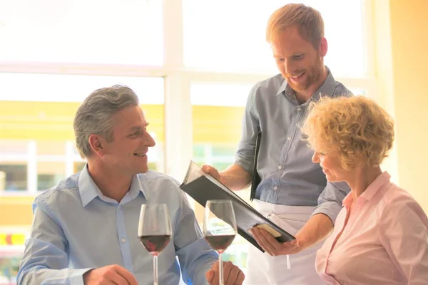 Ung Servitör Visar Meny Till Äldre Par Restaurang — Stockfoto