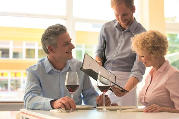 Junger Kellner Zeigt Reiferem Paar Restaurant Speisekarte — Stockfoto