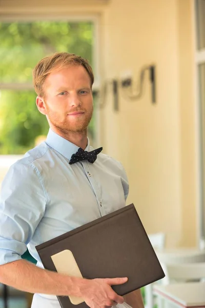 Portrait Confident Young Waiter Holding Menu While Standing Restaurant — Stock Photo, Image