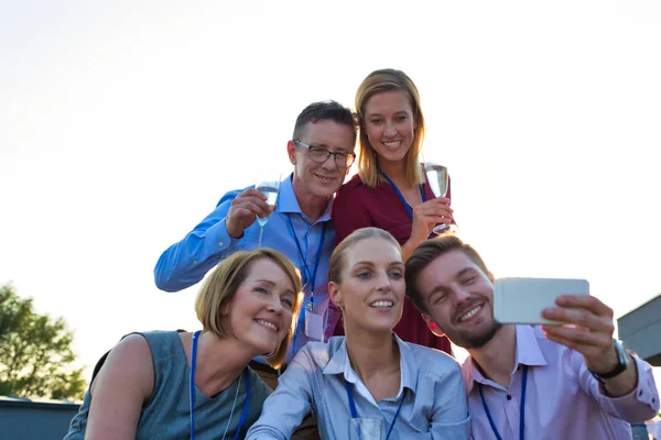 Empresário fazendo selfie com colegas durante festa no terraço — Fotografia de Stock