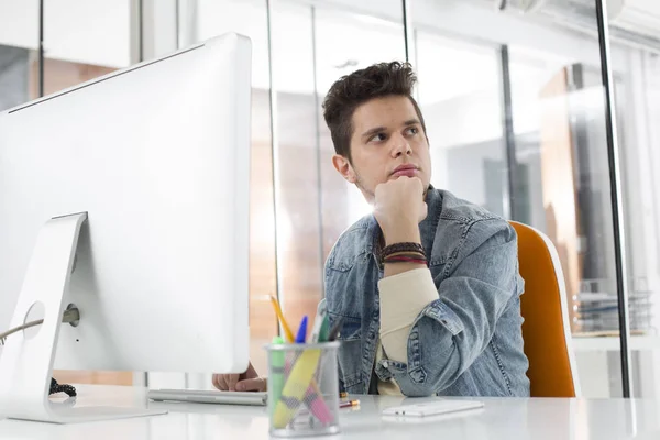 Thoughtful businessman sitting while using computer in office — Stock Photo, Image