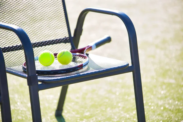 Теннисная ракетка и мяч на стуле на корте — стоковое фото