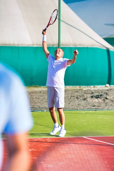 Kendinden emin son sınıf öğrencisi, kort ag 'ında raketle tenis topuna vuruyor. — Stok fotoğraf