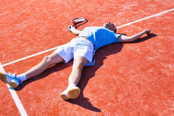 Tam bir hayal kırıklığına uğramış olgun adam tenis raketinin yanında yatıyor. — Stok fotoğraf