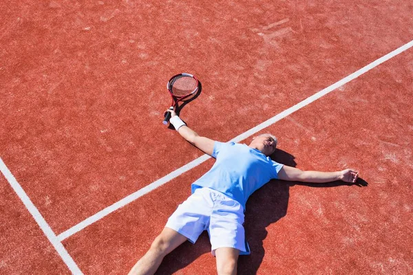 Full längd besviken mogen man som ligger med tennisracket på — Stockfoto