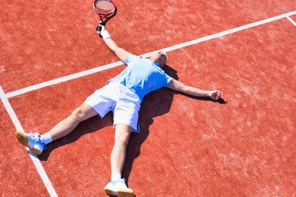 Tam bir hayal kırıklığına uğramış olgun adam tenis raketinin yanında yatıyor. — Stok fotoğraf