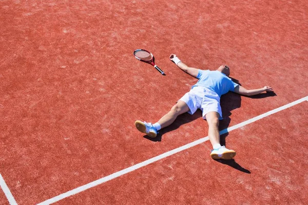 Tam bir hayal kırıklığına uğramış olgun adam tenis raketinin yanında yatıyor. — Stok fotoğraf