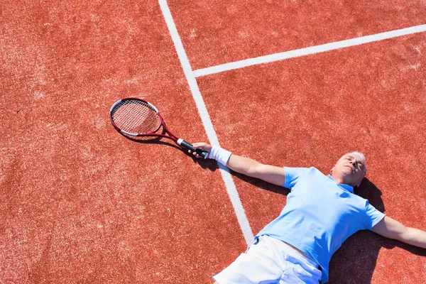 Tam bir hayal kırıklığına uğramış olgun adam tenis raketinin yanında yatıyor. — Stok fotoğraf