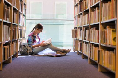 Kitaplık Kütüphane karşı otururken kitap okuma öğrenci