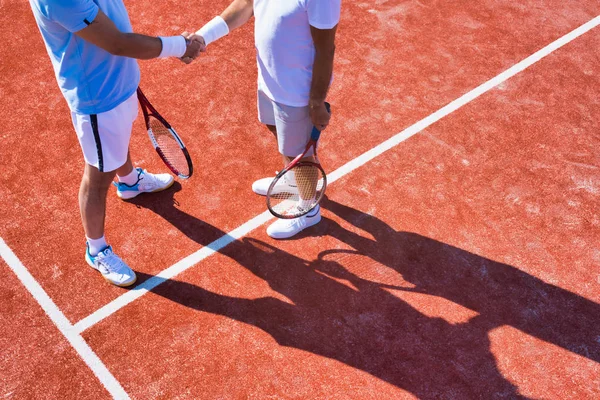 Hombres saludo mientras están de pie en la cancha de tenis durante el partido de verano —  Fotos de Stock