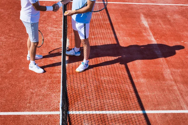 Men greeting while standing on tennis court during summer match — ストック写真