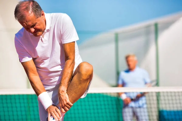 Maturo uomo in piedi mentre soffre di gamba dolore durante partita un — Foto Stock