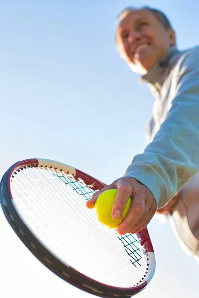 Senior man playing tennis against clear sky on sunny day — ストック写真