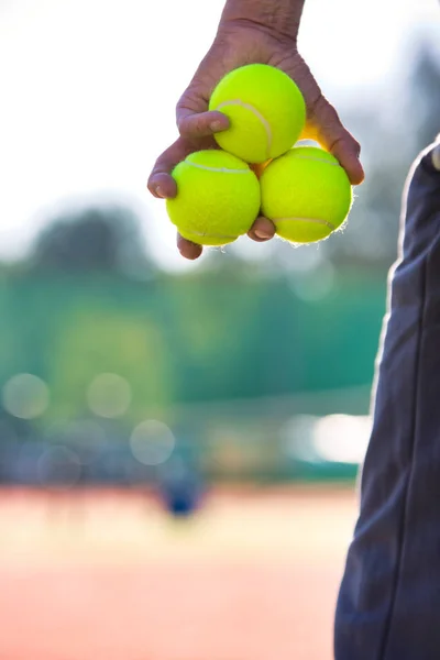 Zdjęcie starszego mężczyzny trzymającego piłki tenisowe na korcie — Zdjęcie stockowe