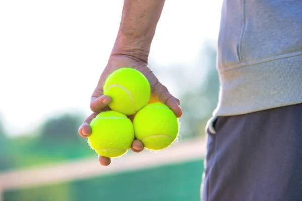 Фото літнього чоловіка, який тримає тенісні м'ячі на корті — стокове фото