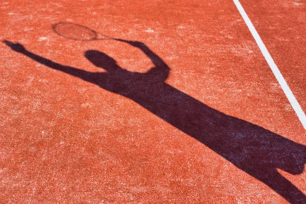 Skugga mogen man slå tennisboll med racket på röd cour — Stockfoto
