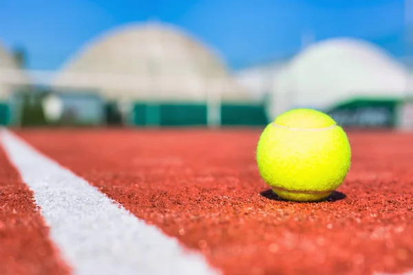 Μπάλα τένις στο κόκκινο γήπεδο κατά τη διάρκεια της ηλιόλουστης ημέρας — Φωτογραφία Αρχείου
