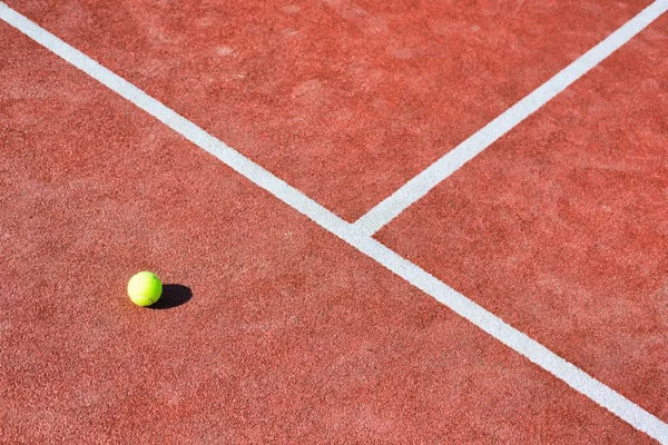 Теннисный мяч на красной площадке в солнечный день — стоковое фото