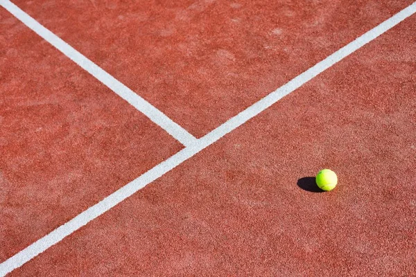 Tennisboll på röd bana under solig dag — Stockfoto