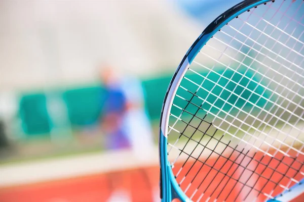 Photo of tennis racket against friend playing match on court — ストック写真