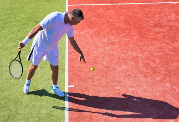 Pewny siebie dojrzały mężczyzna gra w tenisa w słoneczny dzień — Zdjęcie stockowe