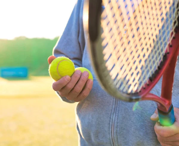 Homem segurando raquete tenis e bola na quadra no dia ensolarado — Fotografia de Stock