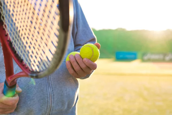 Homem segurando raquete tenis e bola na quadra no dia ensolarado — Fotografia de Stock