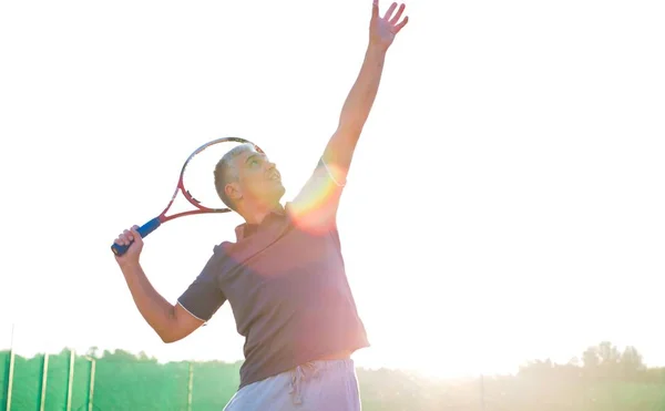 Volwassen man raken tennis bal tegen heldere hemel — Stockfoto