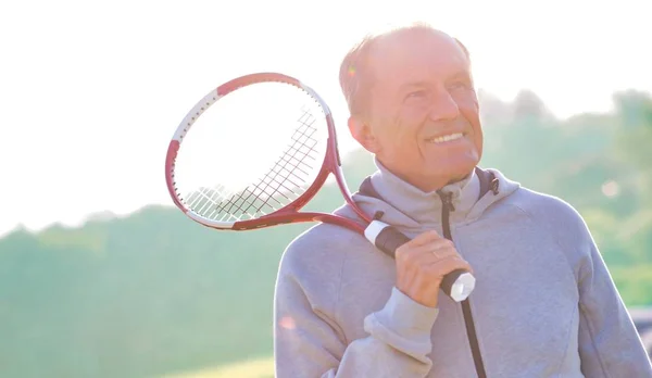 Atrás iluminado de hombre confiado sosteniendo pelota de tenis y raqueta en cour —  Fotos de Stock