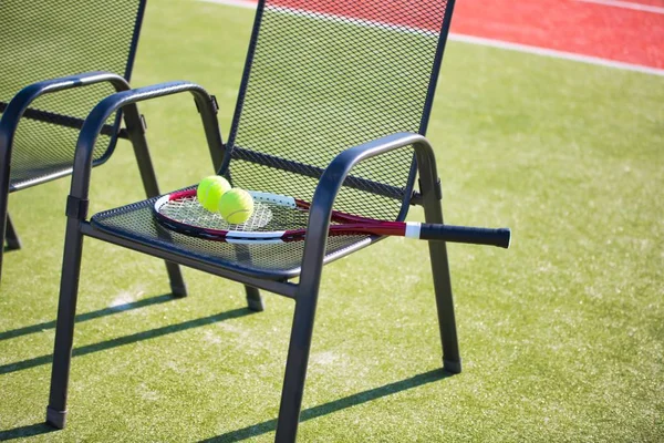 Фото теннисной ракетки и мяча на стуле на корте — стоковое фото