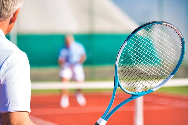 Actieve senioren tennissen op zonnige dag aan de rode baan — Stockfoto