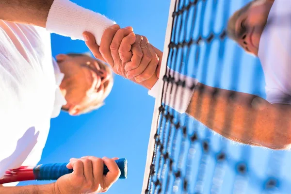 Vue à angle bas des hommes serrant la main en se tenant debout au tennis cou — Photo