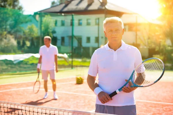 Glimlachende Volwassen Man Houden Tennis Racket Met Teamgenoot Aan Achterkant — Stockfoto