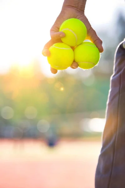 Person holding three tennis balls in left hand