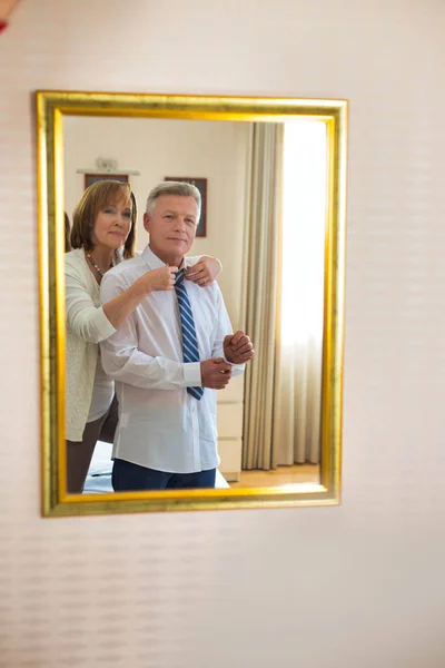Mature woman adjusting necktie of businessman while looking on t — ストック写真