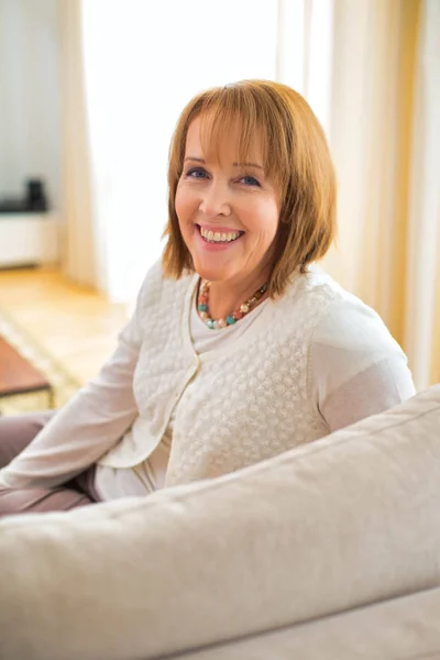 Portrait of smiling woman sitting on sofa — Stock Photo, Image