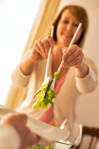 Leende kvinna som serverar sallad till man hemma — Stockfoto