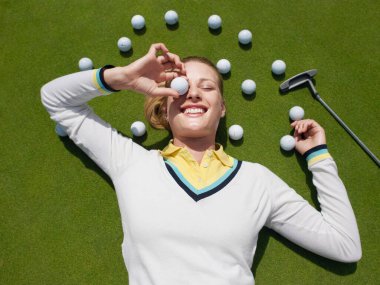 Genç bayan golfçü yeşil topun üzerinde yatıyordu.