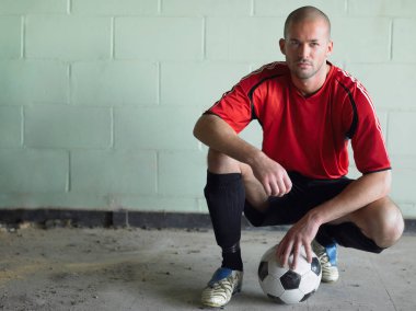Futbolcu, top portresiyle çömeldi.