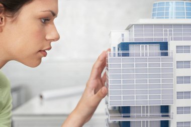 Mimari model profilini yakından inceleyen yetişkin bir kadın.