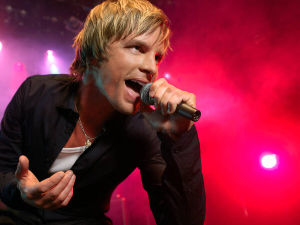 Young Man Singing into microphone on stage at Concert low angle view