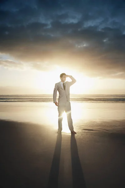 夕暮れ時にビーチに立つビジネスマン — ストック写真