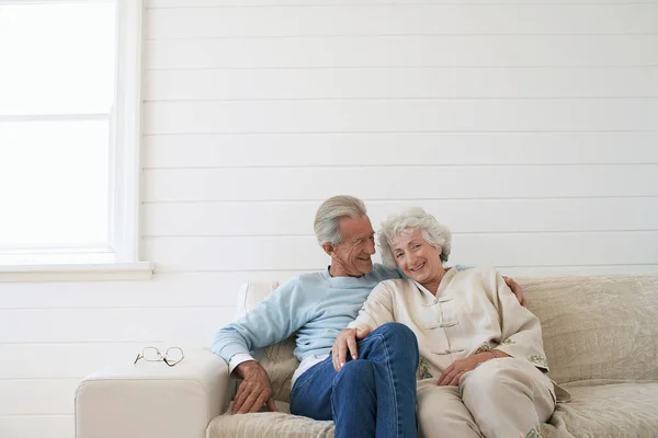 Yaşlı Çift Kanepede Oturmuş Gülümsüyor — Stok fotoğraf
