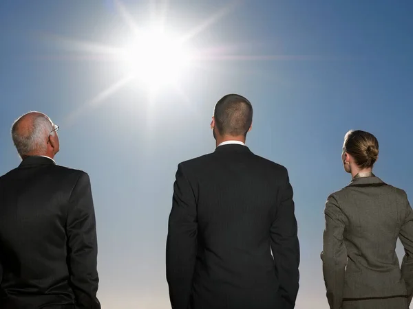 太陽を仰ぎ見るスーツ姿のビジネスマン3人の後ろ姿 — ストック写真
