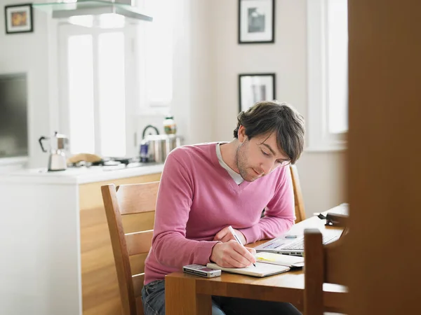 Hombre Sentado Cocina Escribiendo Cuaderno —  Fotos de Stock