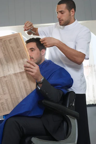 Biznes Czyta Gazetę Fryzjer Strzyżenie Włosów Salonie Fryzjerskim — Zdjęcie stockowe