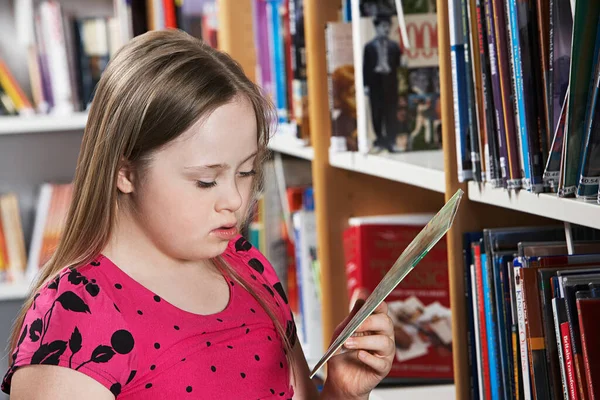 患有唐氏综合征的女孩 12岁 在书架上看书 — 图库照片