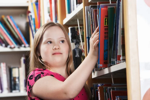 患有唐氏综合征的女孩 12岁 从书架上取书 — 图库照片